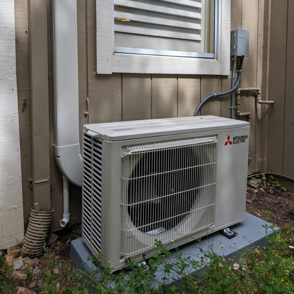Outdoor mini-split condenser mounted beneath a window