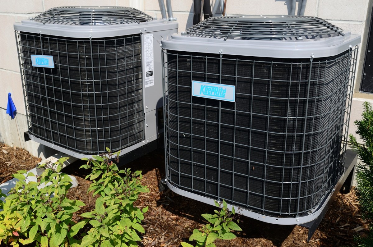 Two large outdoor hvac units with "keeprite" logos, installed beside a building, surrounded by small plants in sunlight.