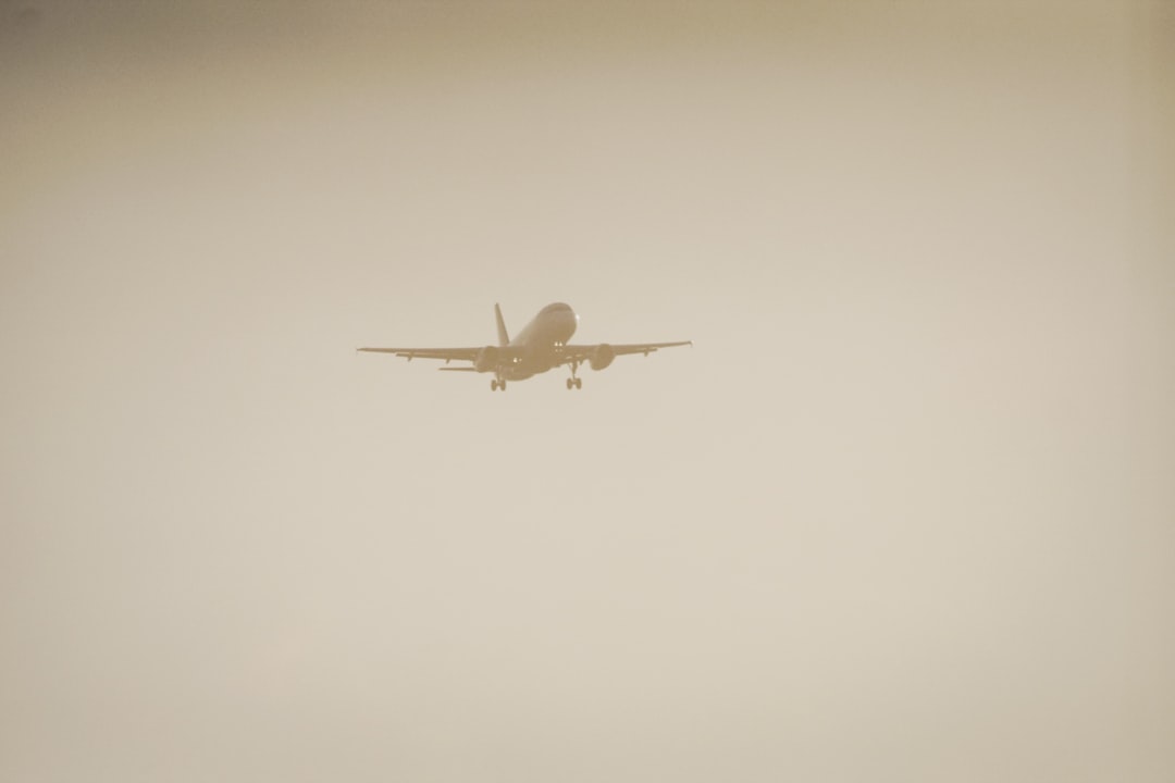 A commercial airplane is flying in the sky with its landing gear extended, silhouetted against a hazy, light background—perhaps wishing for an air conditioner on the hottest day. A commercial airplane is flying in the sky with its landing gear extended, silhouetted against a hazy, light background—perhaps wishing for an air conditioner on the hottest day.