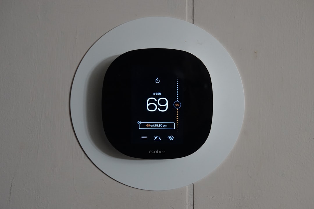 A black Ecobee smart thermostat is mounted on a white wall, displaying a current temperature setting of 69 degrees Fahrenheit—a sleek thermostat replacement offering advanced smart controls for modern home comfort.